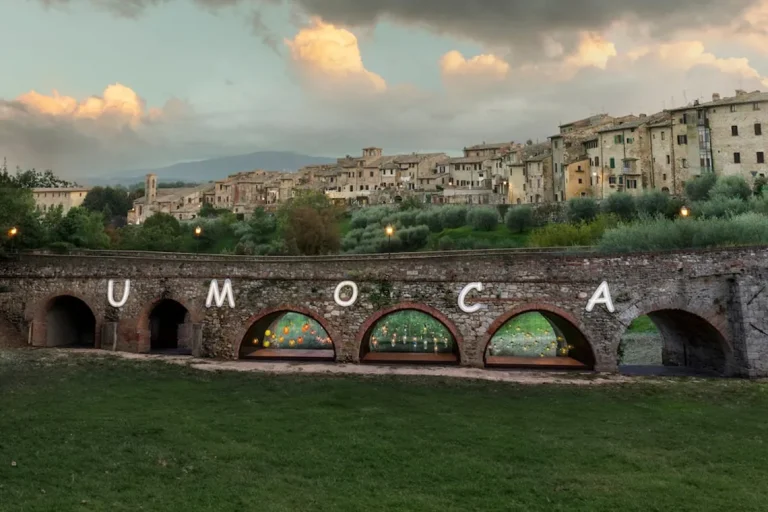 Veduta del ponte di San Francesco a Colle di Val d’Elsa con la scritta luminosa UMoCA che indica se è aperta una mostra sotto le arcate del ponte